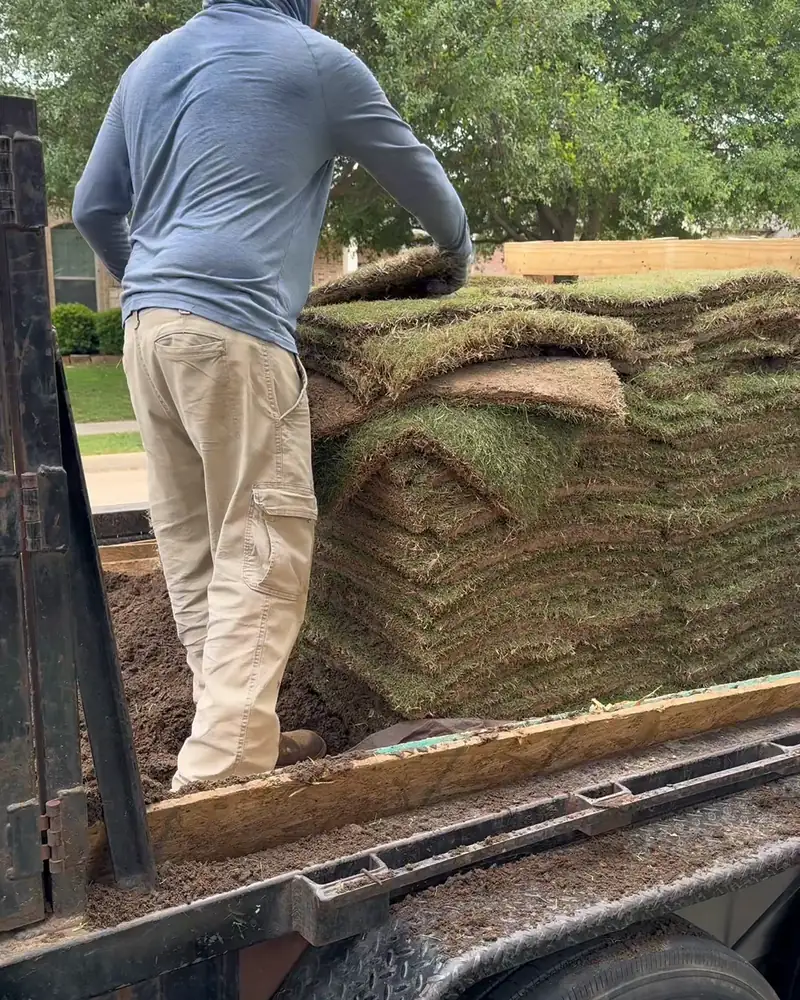 Crew member unloading pallets of sod